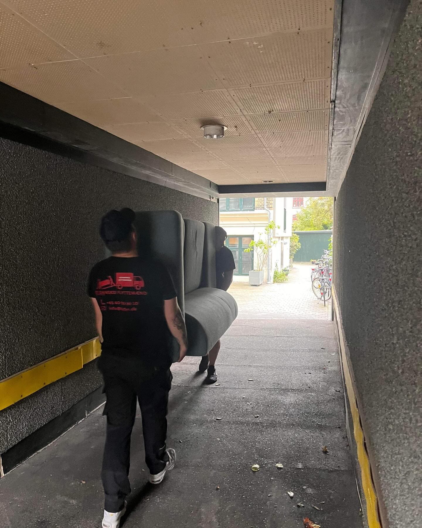 To flyttemænd bærer en sofa gennem en port.